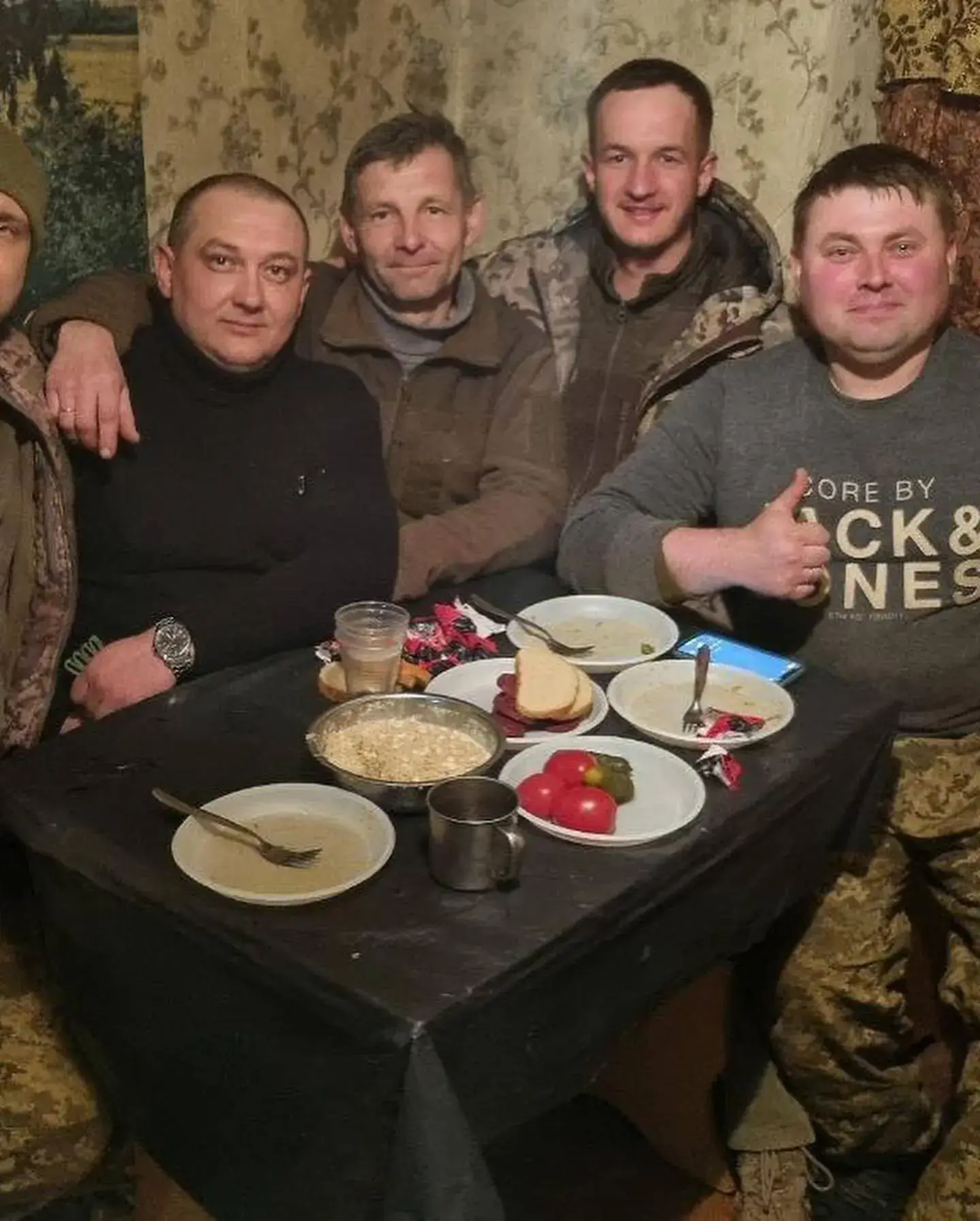 a group of men sitting around a table with food on it.