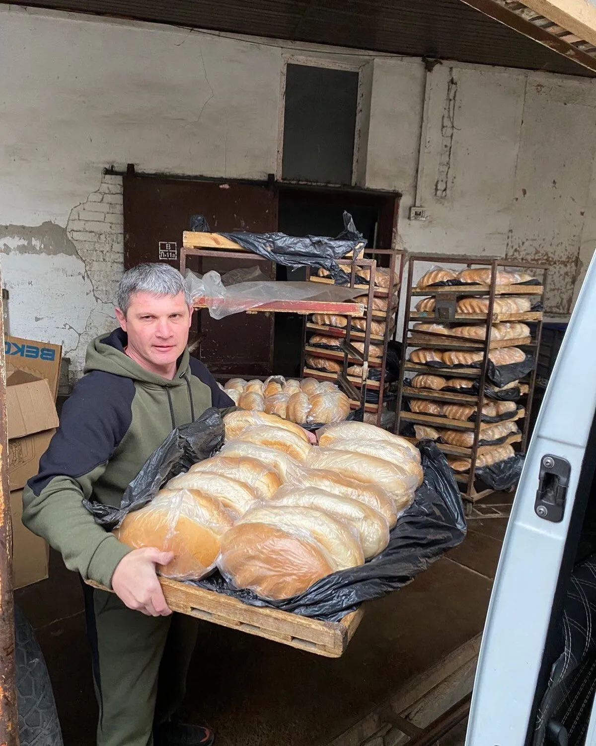a man holding a large tray of bread.