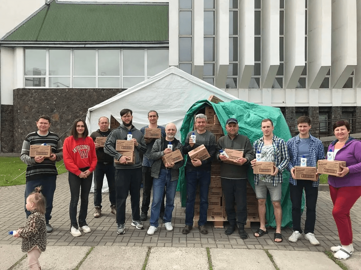 a group of people holding boxes in front of a building.