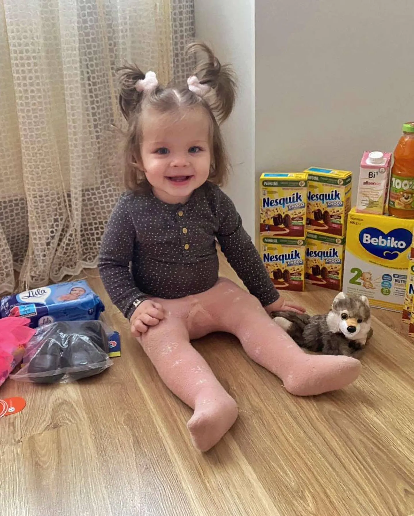 a little girl sitting on the floor with her toys.