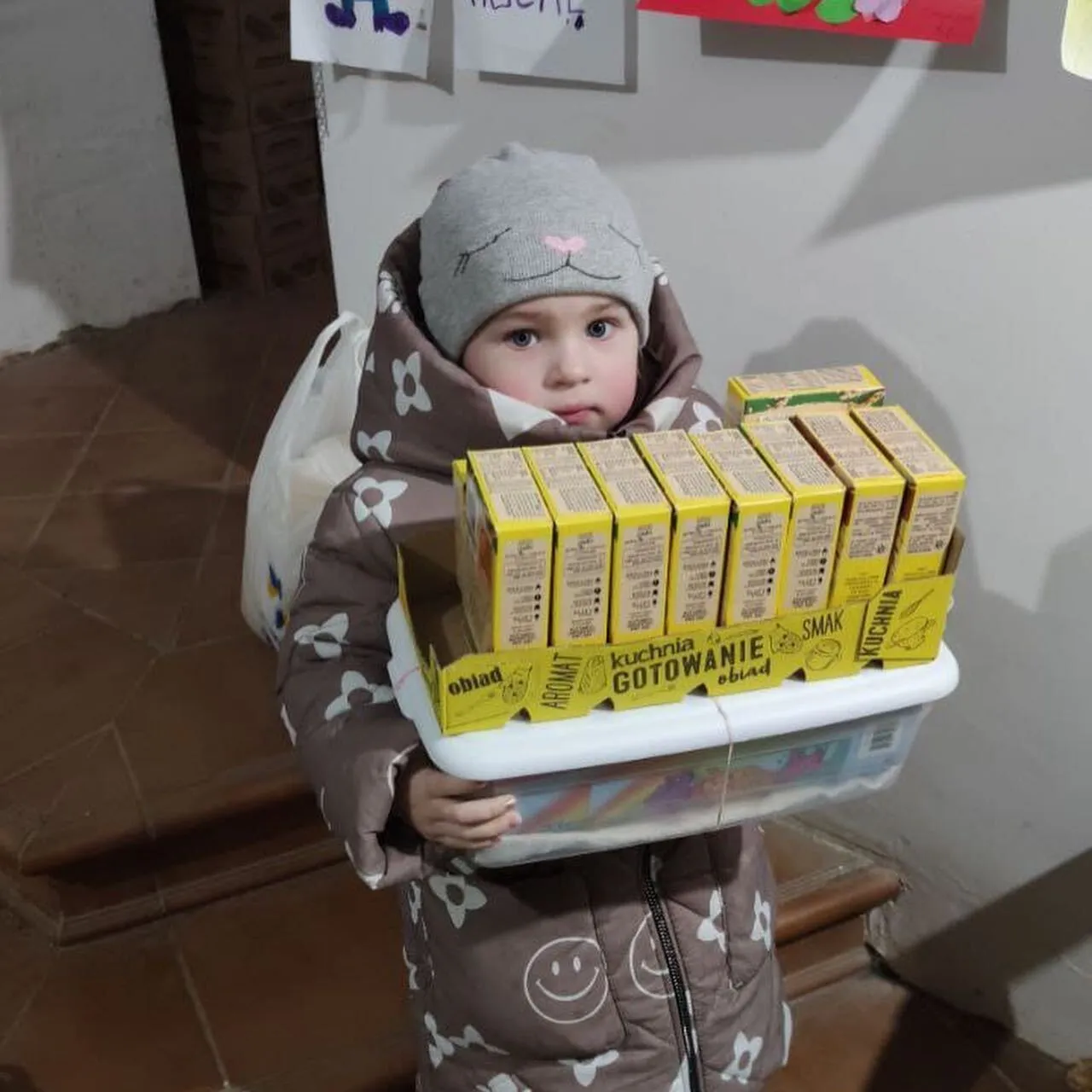 a small child holding a tray of boxes.