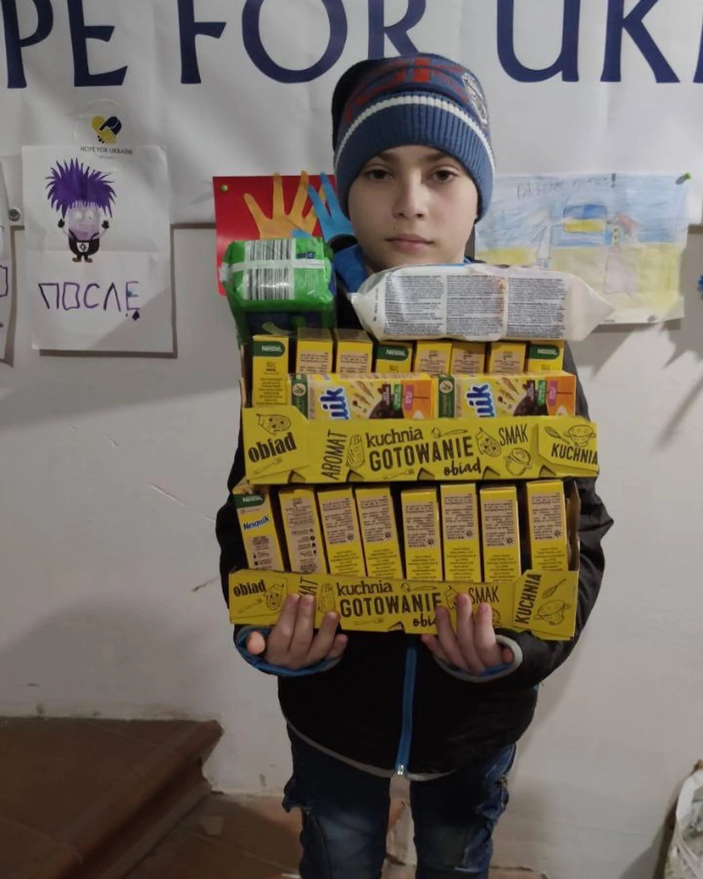 a young boy holding up a stack of boxes.