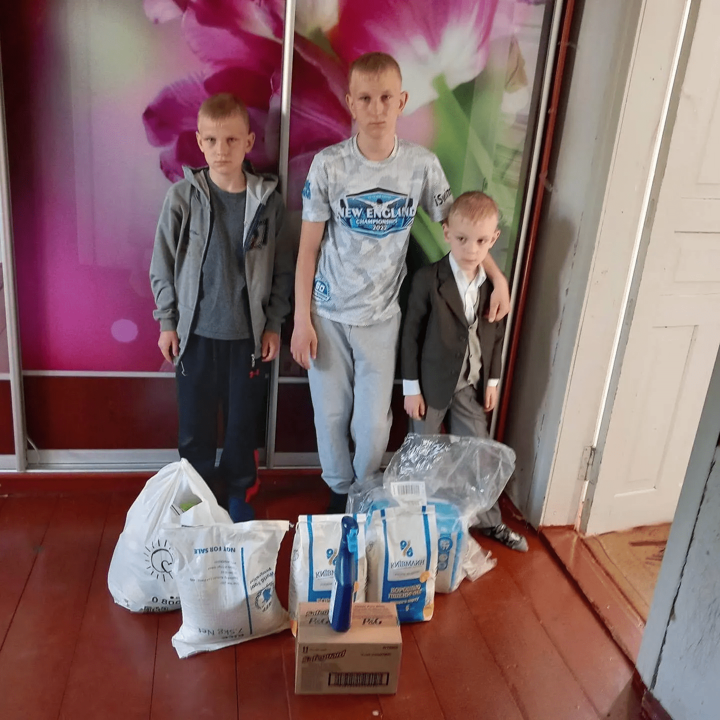 three young boys standing next to a pile of bags.