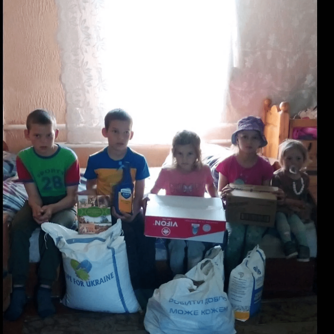 a group of children sitting on a couch holding boxes.