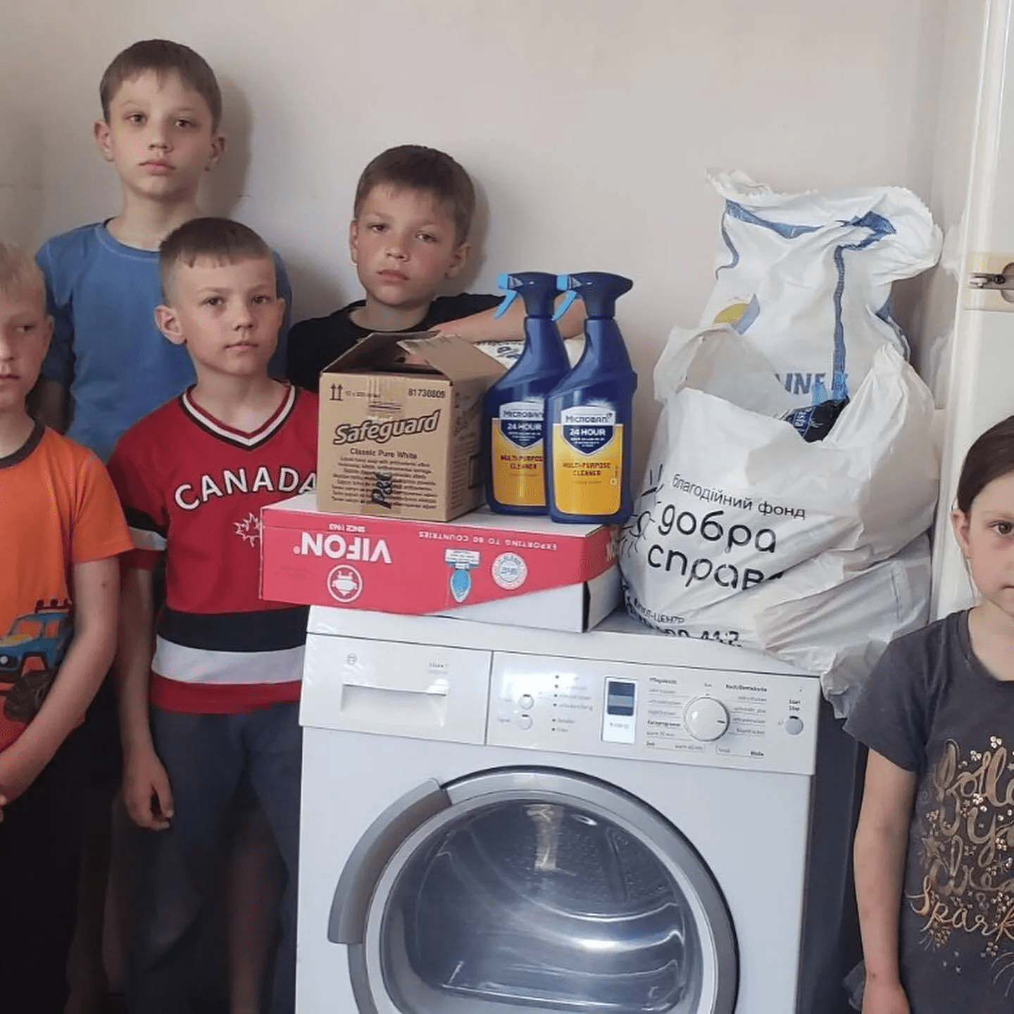 a group of children standing next to a washing machine.