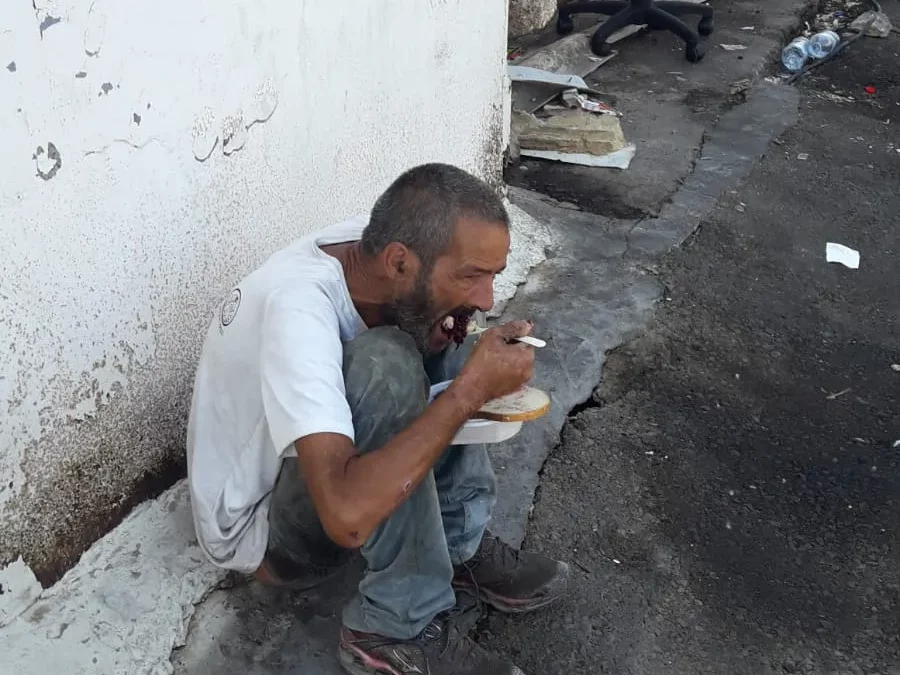 a man sitting on the ground eating food.