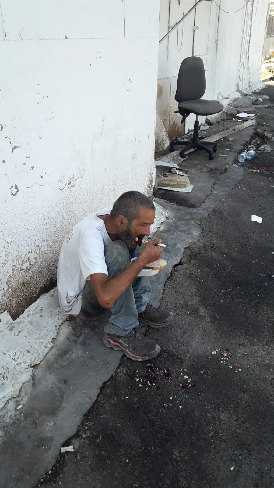 a man sitting on the ground eating food.