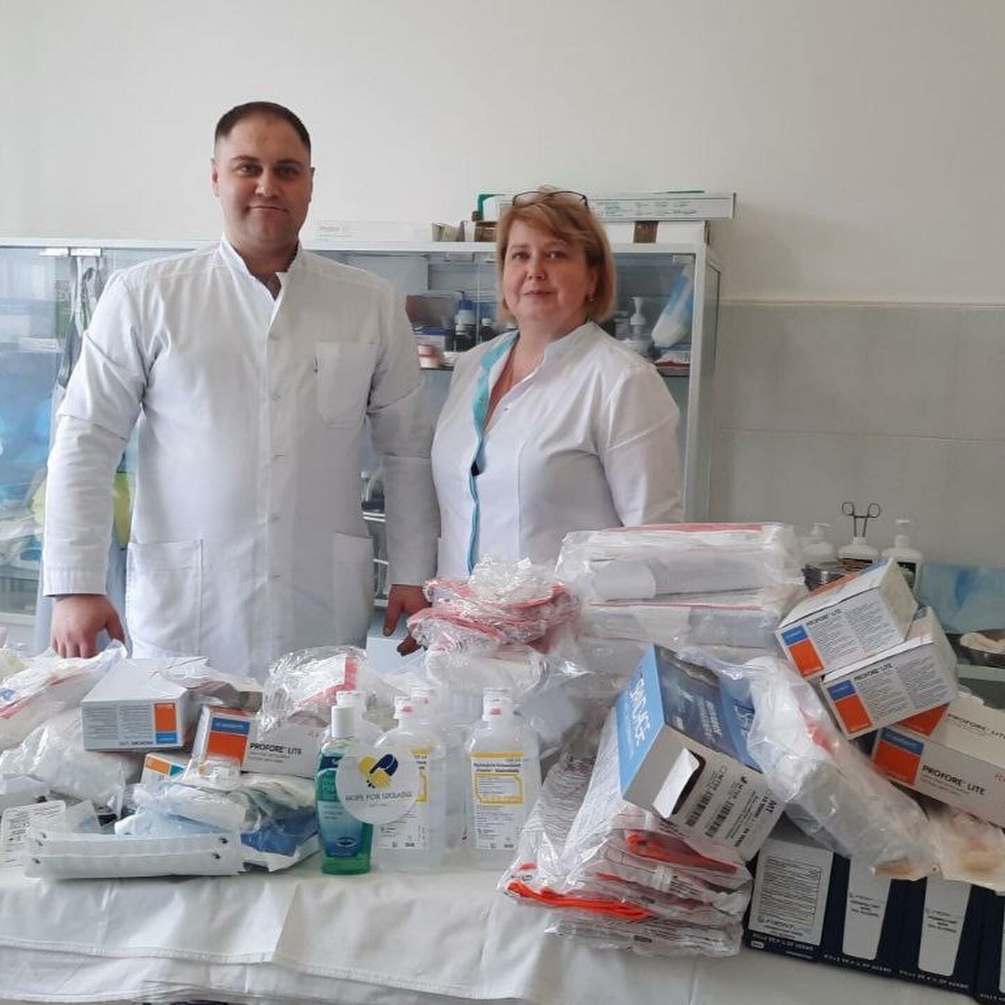 a man and a woman standing next to a table full of medical supplies.
