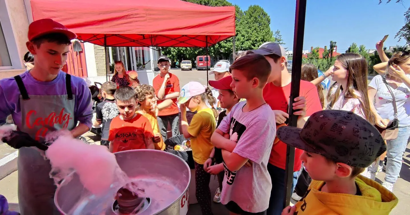 a group of children standing around a bucket of liquid.