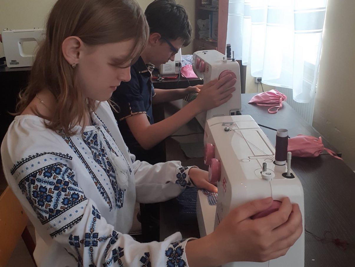 two girls are working on a sewing machine.