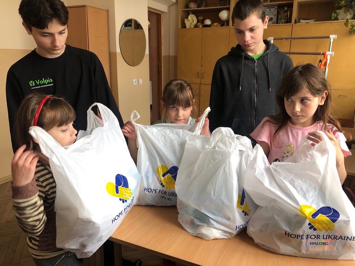 a group of young children holding bags of food.