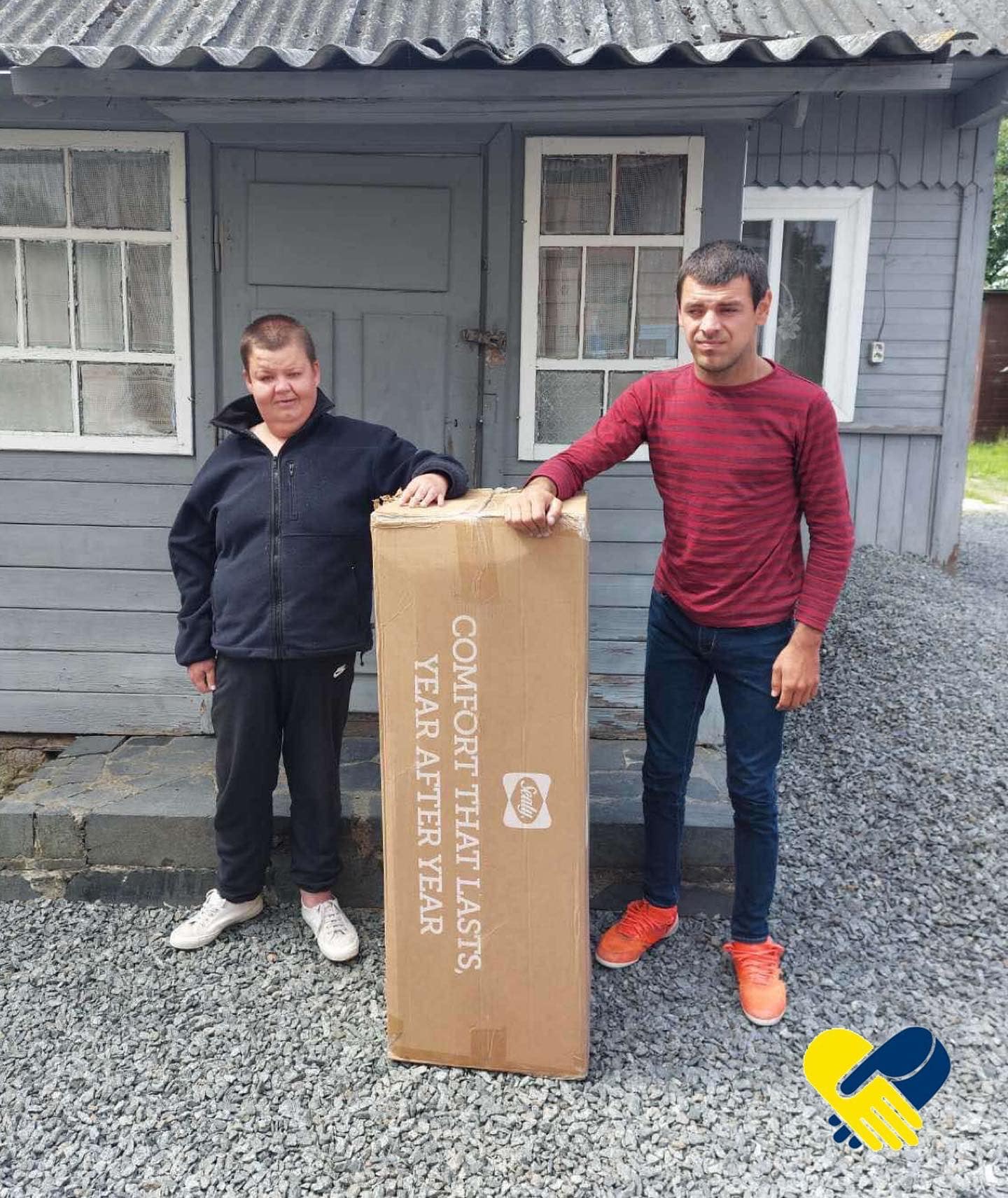 two men standing next to a cardboard box.