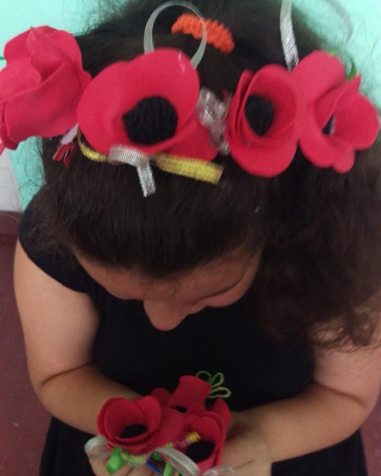 a little girl wearing a red flower headband.