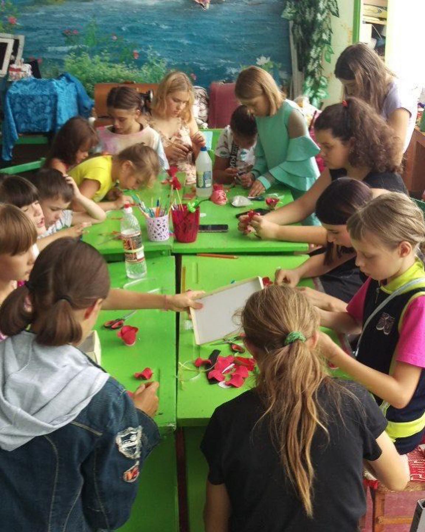 a group of children sitting around a green table.