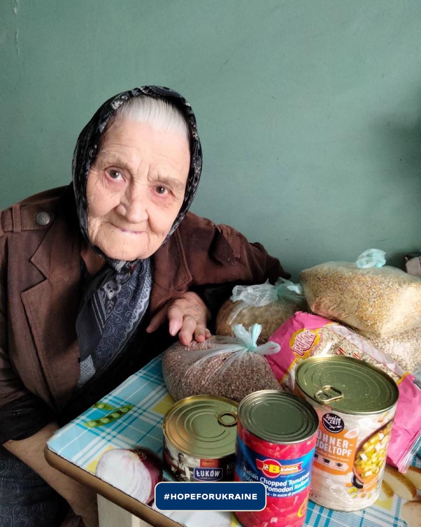 an elderly woman sitting at a table with canned food.