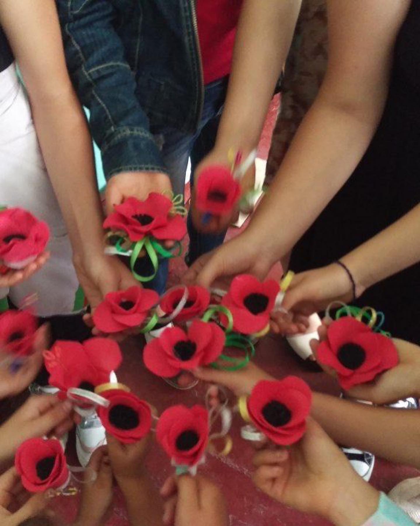 a group of people standing around each other holding red flowers.