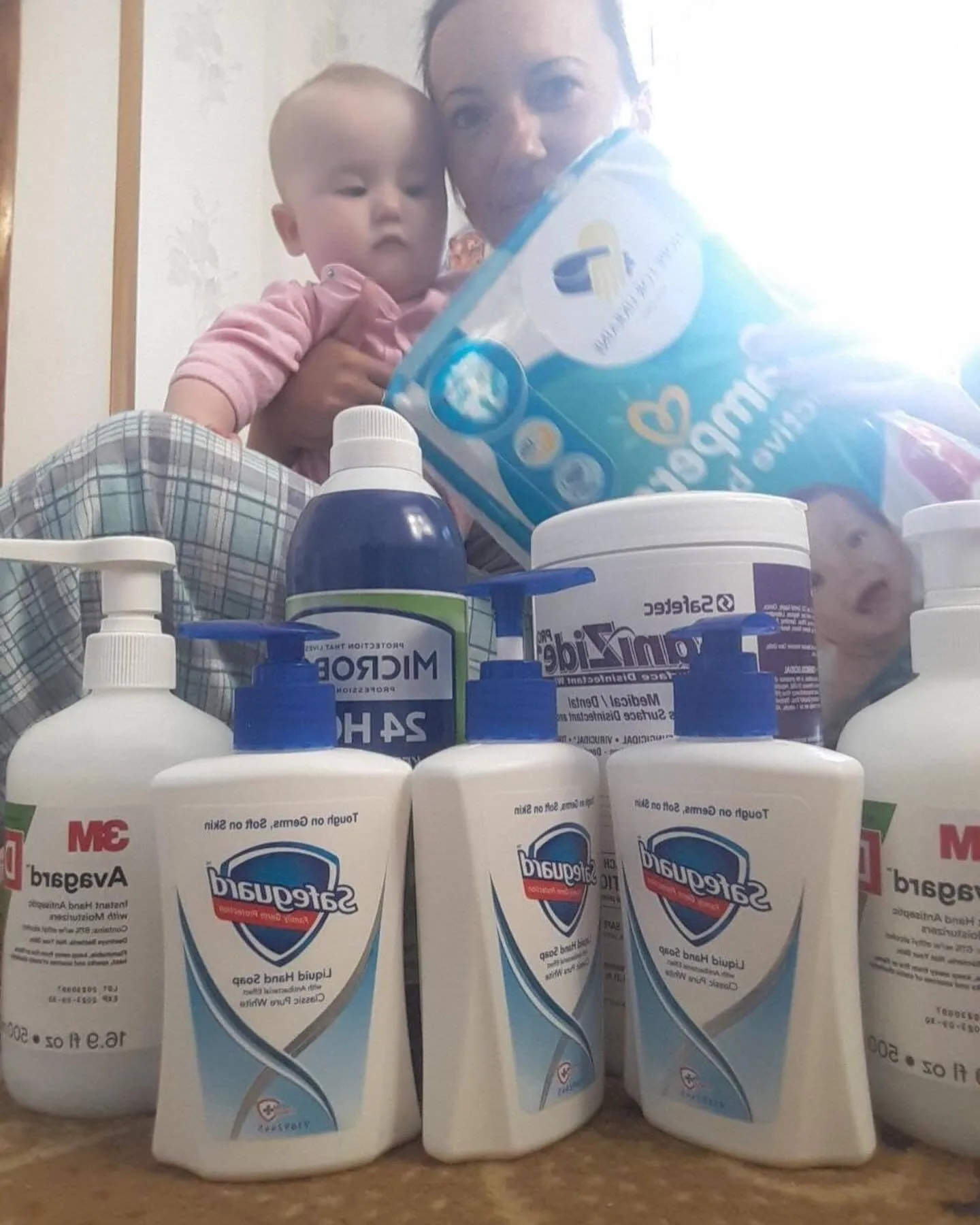 a woman holding a baby in front of bottles of mouthwash.