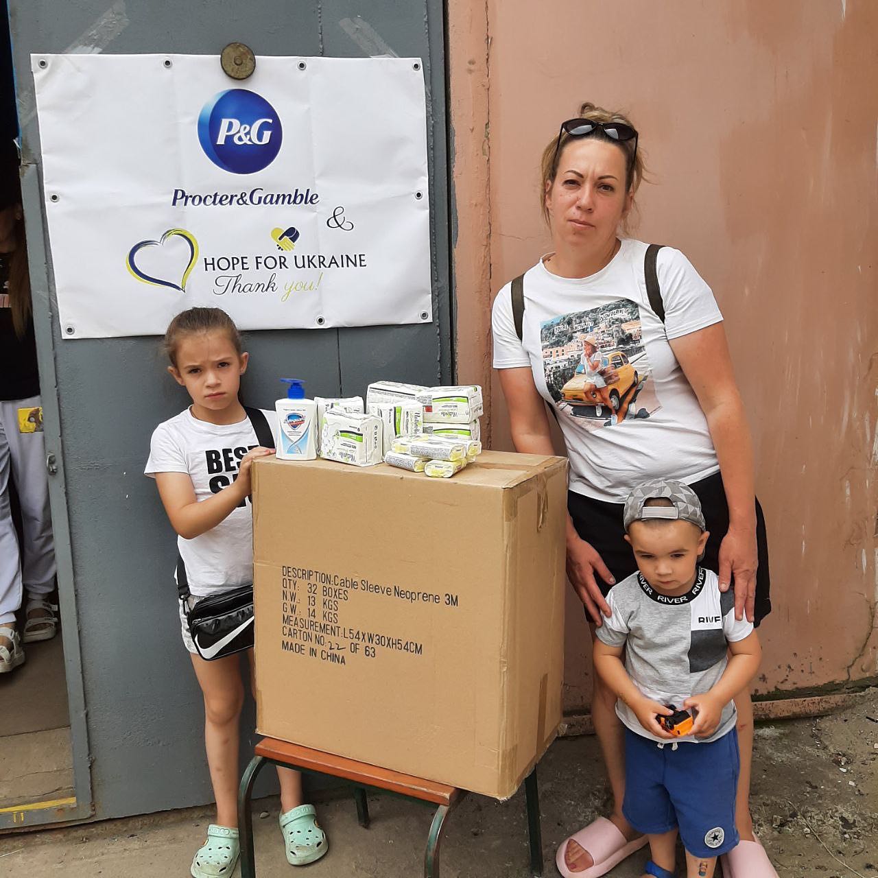 a woman and two children standing next to a cardboard box.