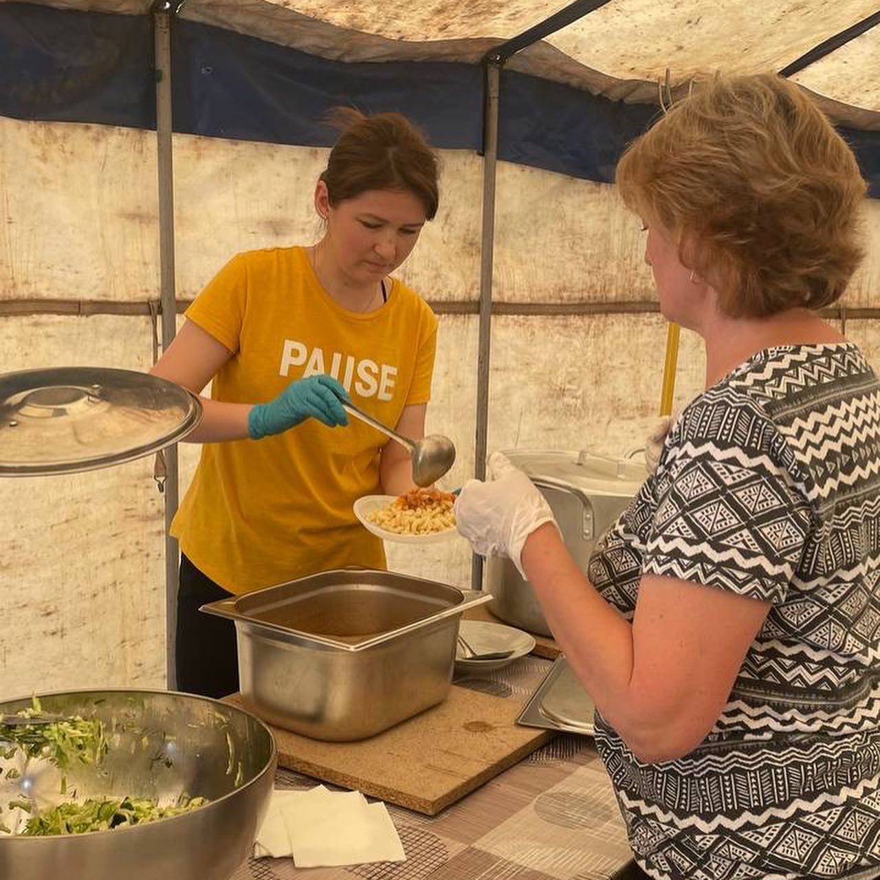 a woman in a yellow shirt is serving food to another woman.