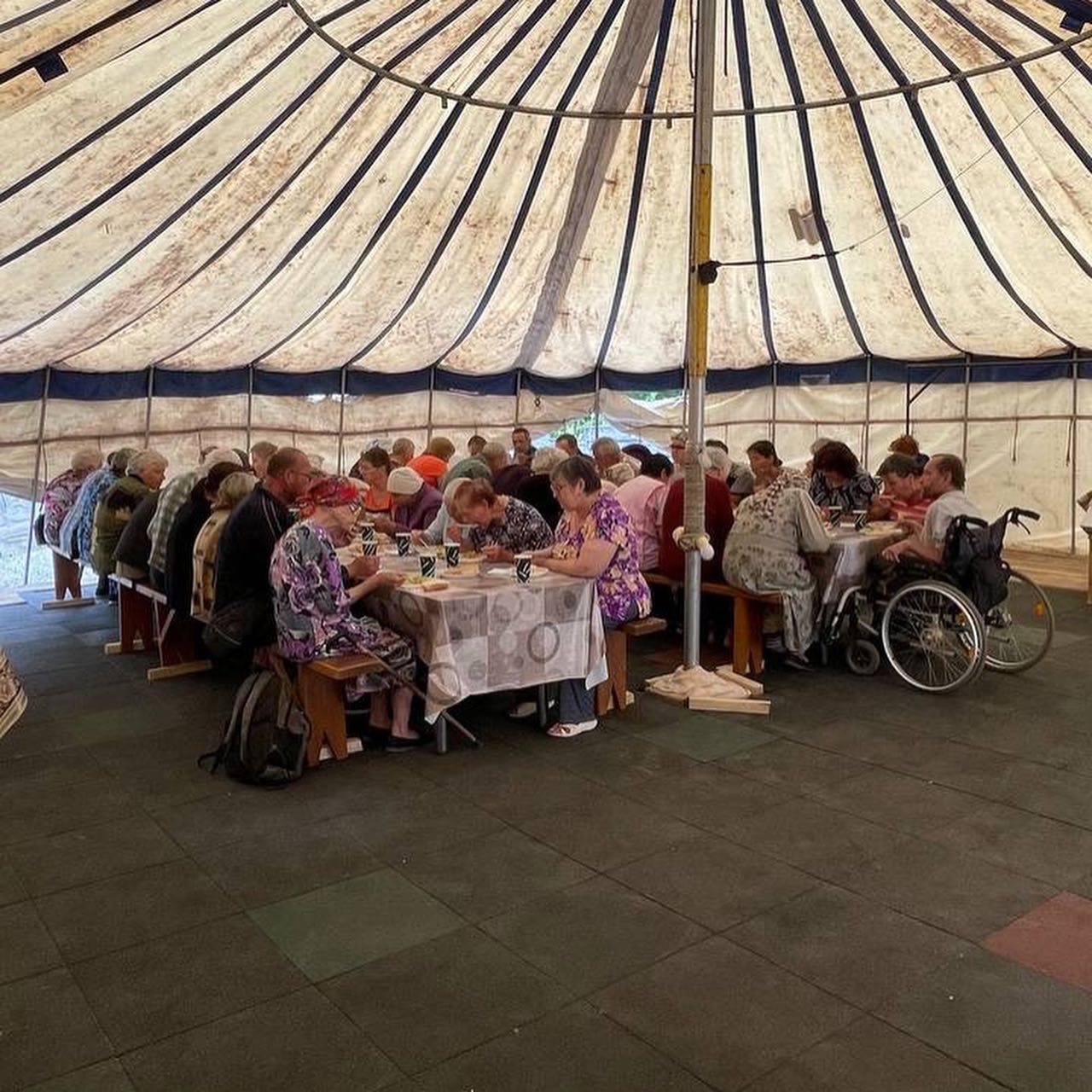 a group of people sitting around a table under a tent.