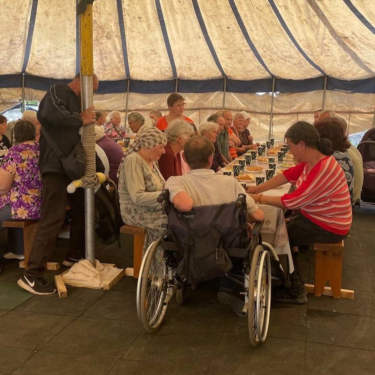 a group of people sitting at tables under a tent.