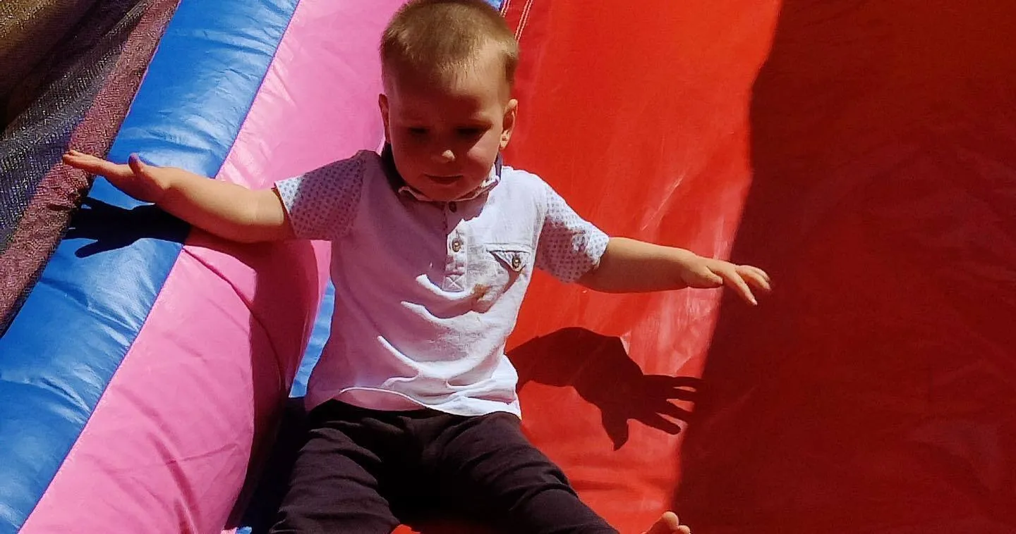 a little boy sitting on top of a slide.