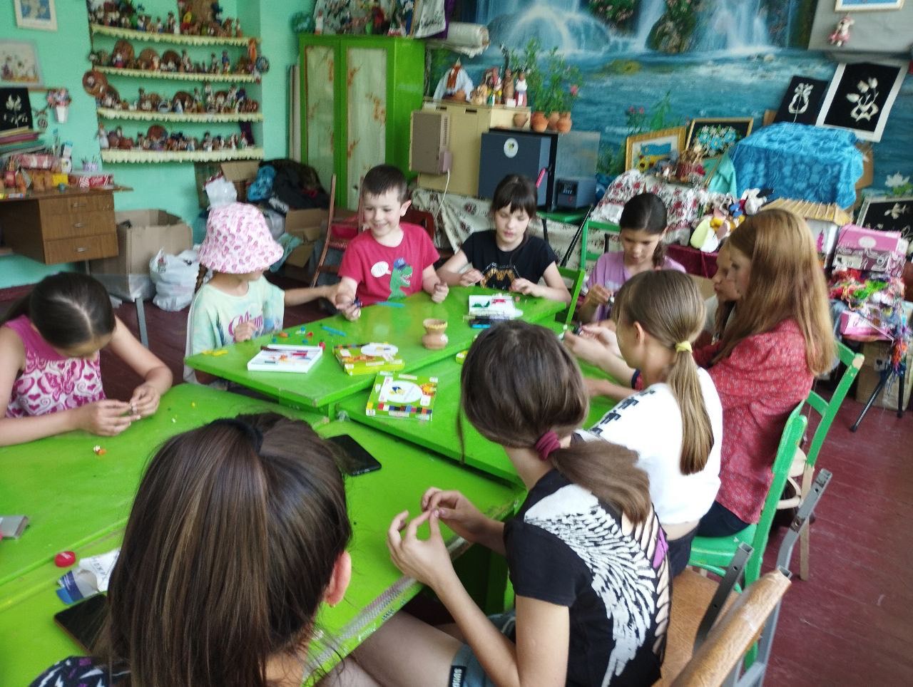 a group of children sitting around a green table.