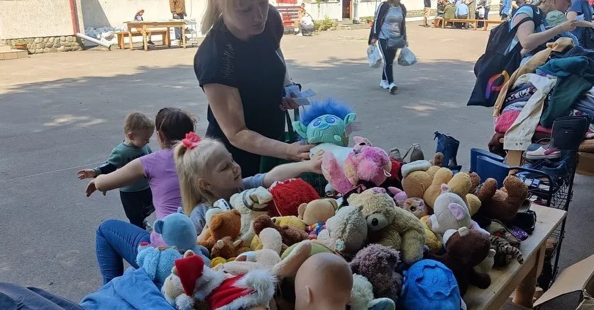 a woman and a child looking at a pile of stuffed animals.