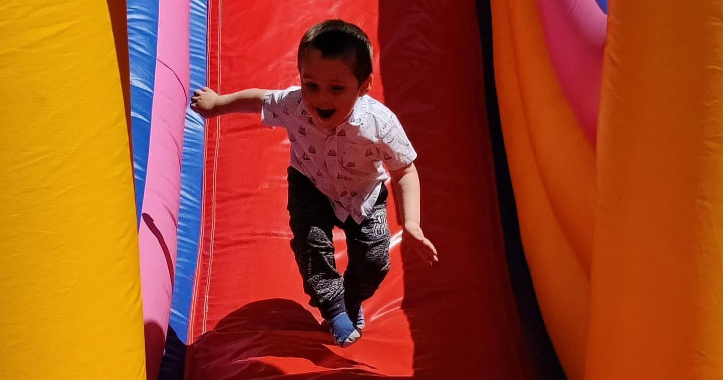 a little girl is sliding down a bouncy castle.