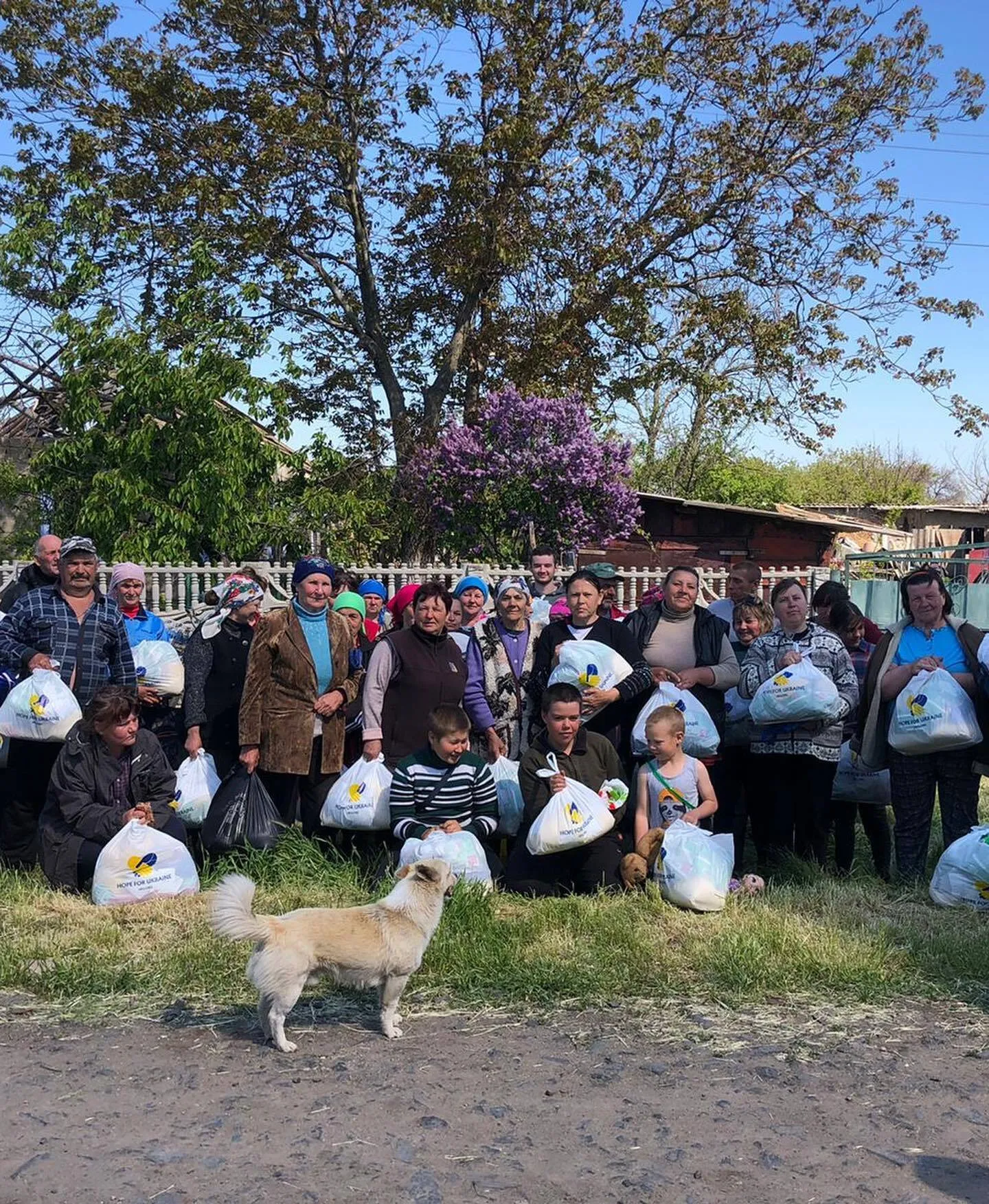 a group of people holding bags with a dog standing next to them.
