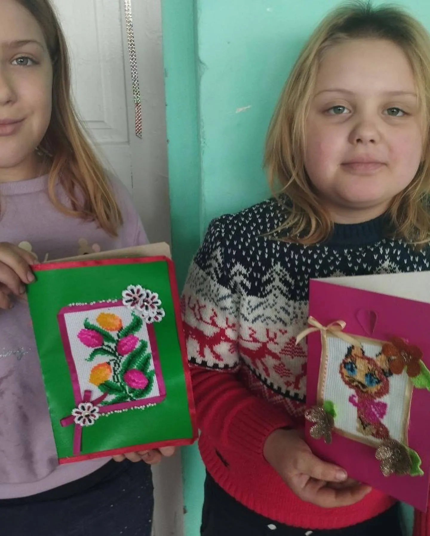 two young girls are holding small cards and a picture.