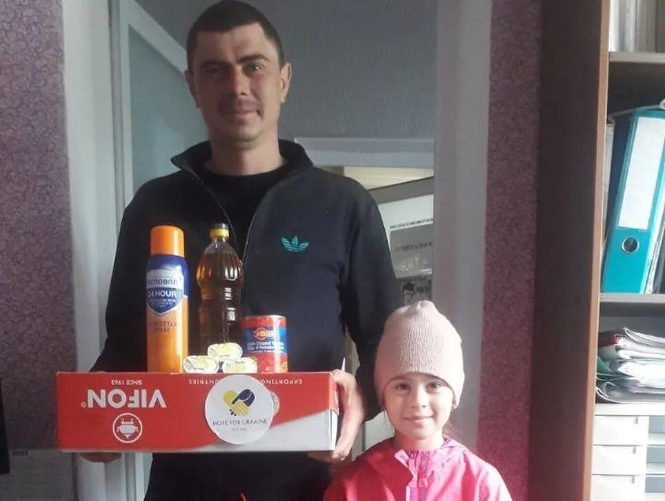 a man standing next to a little girl holding a pizza box.