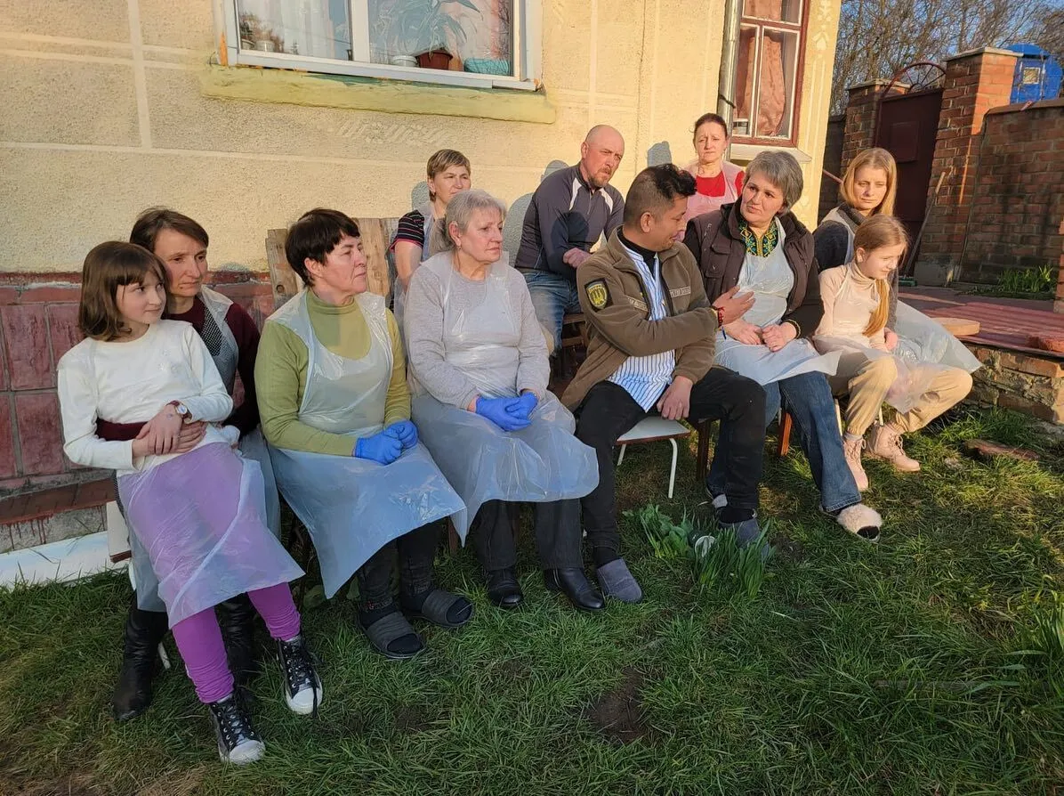 a group of people sitting on a bench in front of a house.