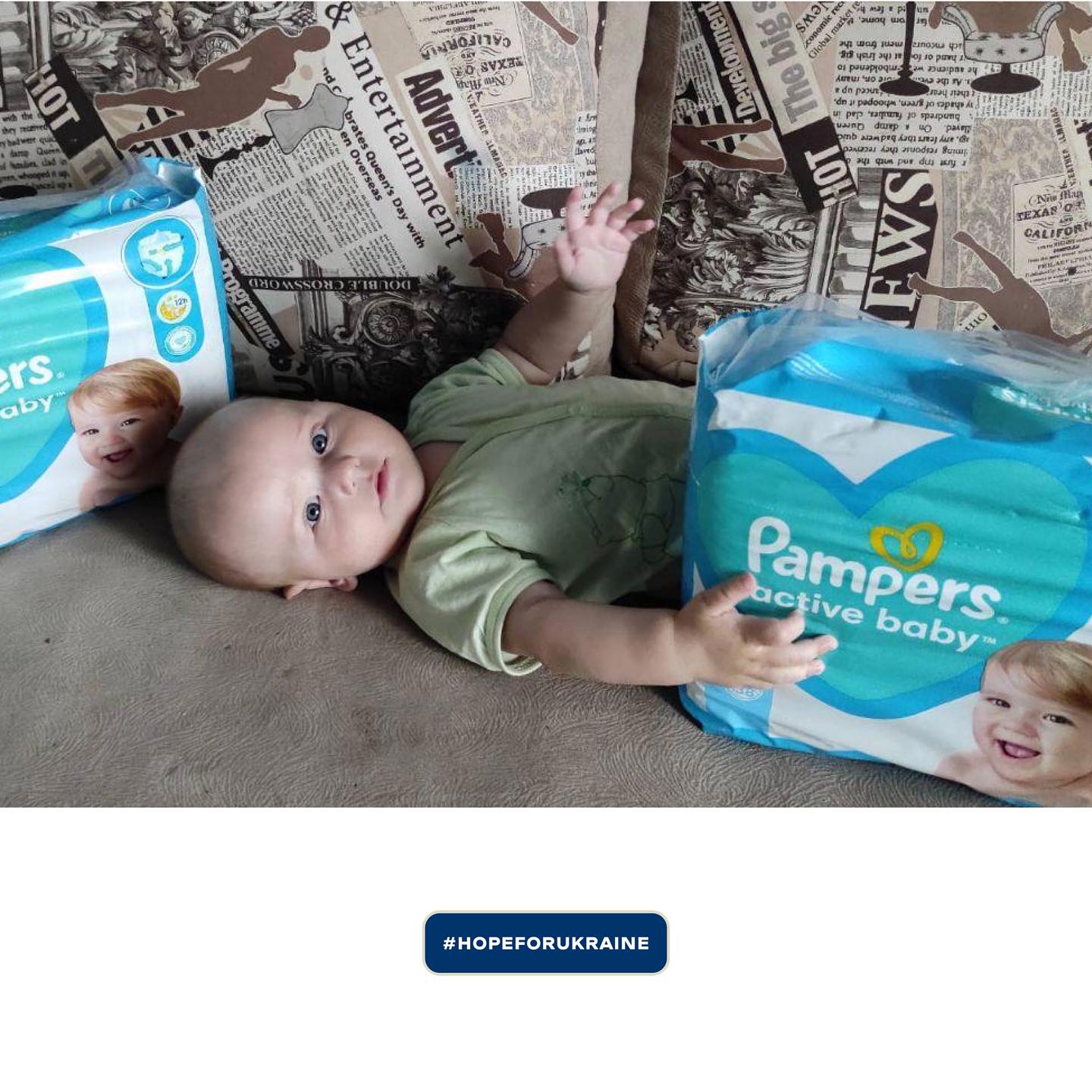 a baby is laying on a couch next to two packs of pampers diapers.