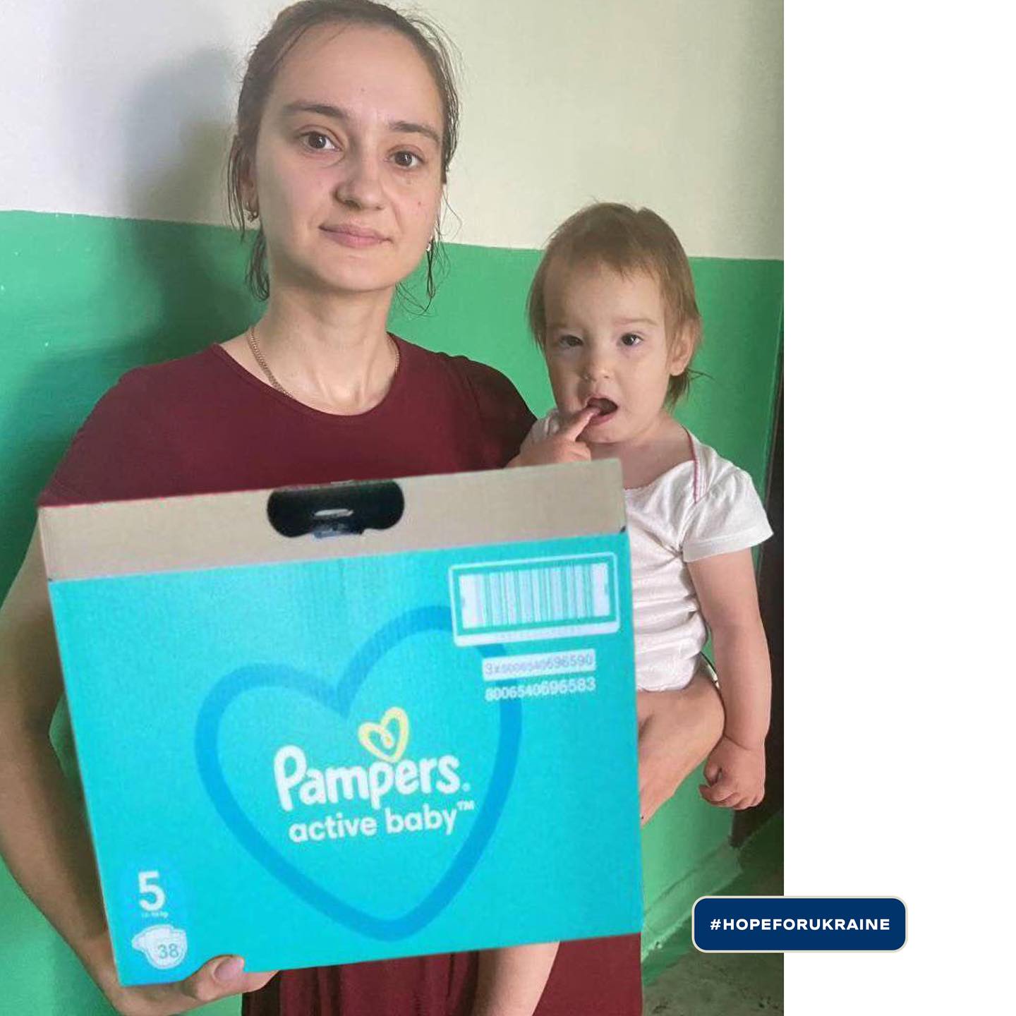 a woman with a baby holding a box of pampers diapers.