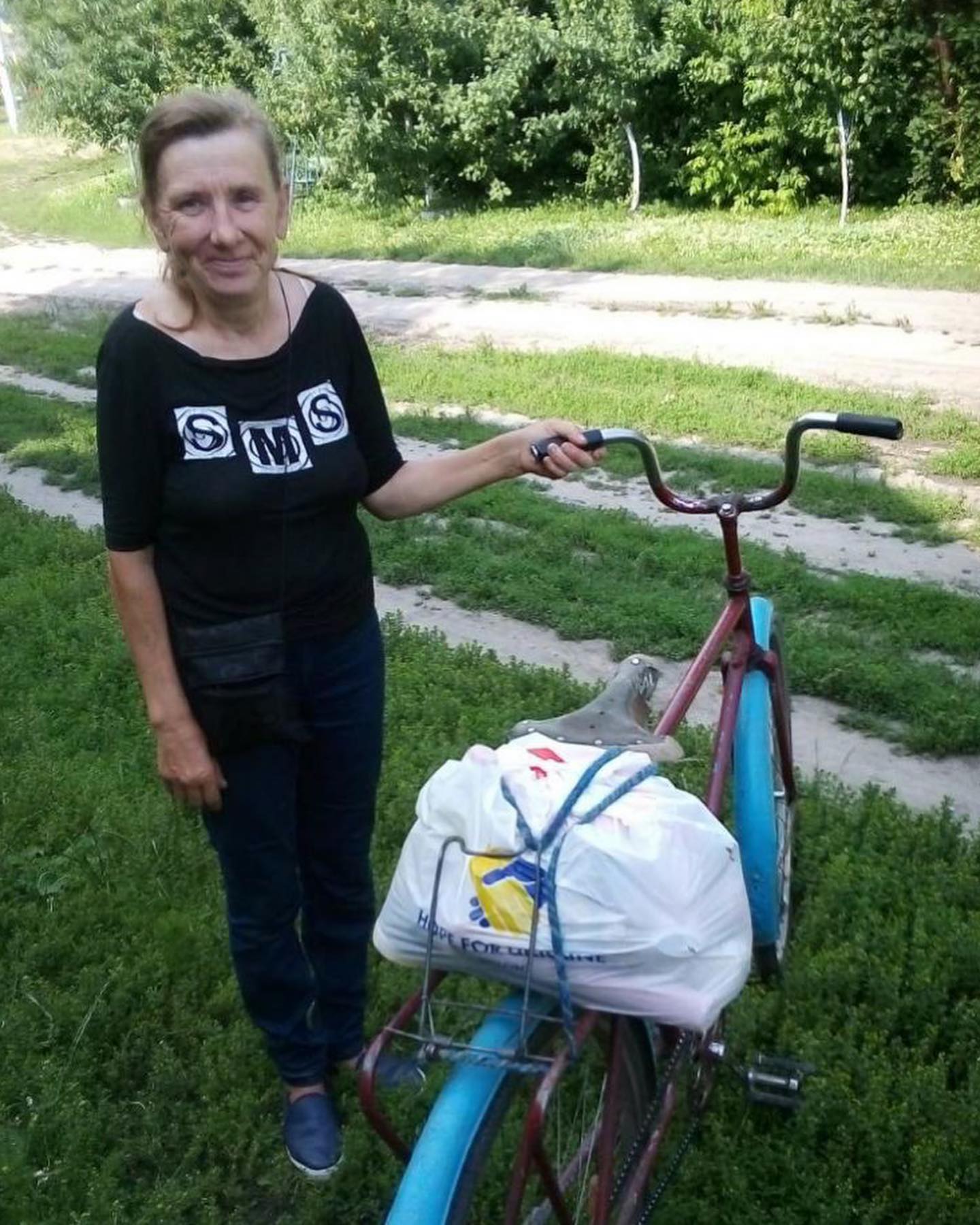 a woman standing next to a bike with a bag on it.