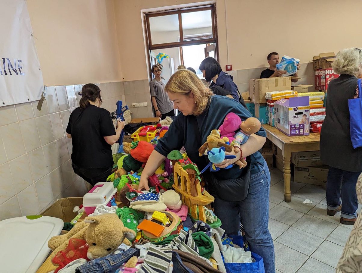 a woman sorting through stuffed animals in a room.
