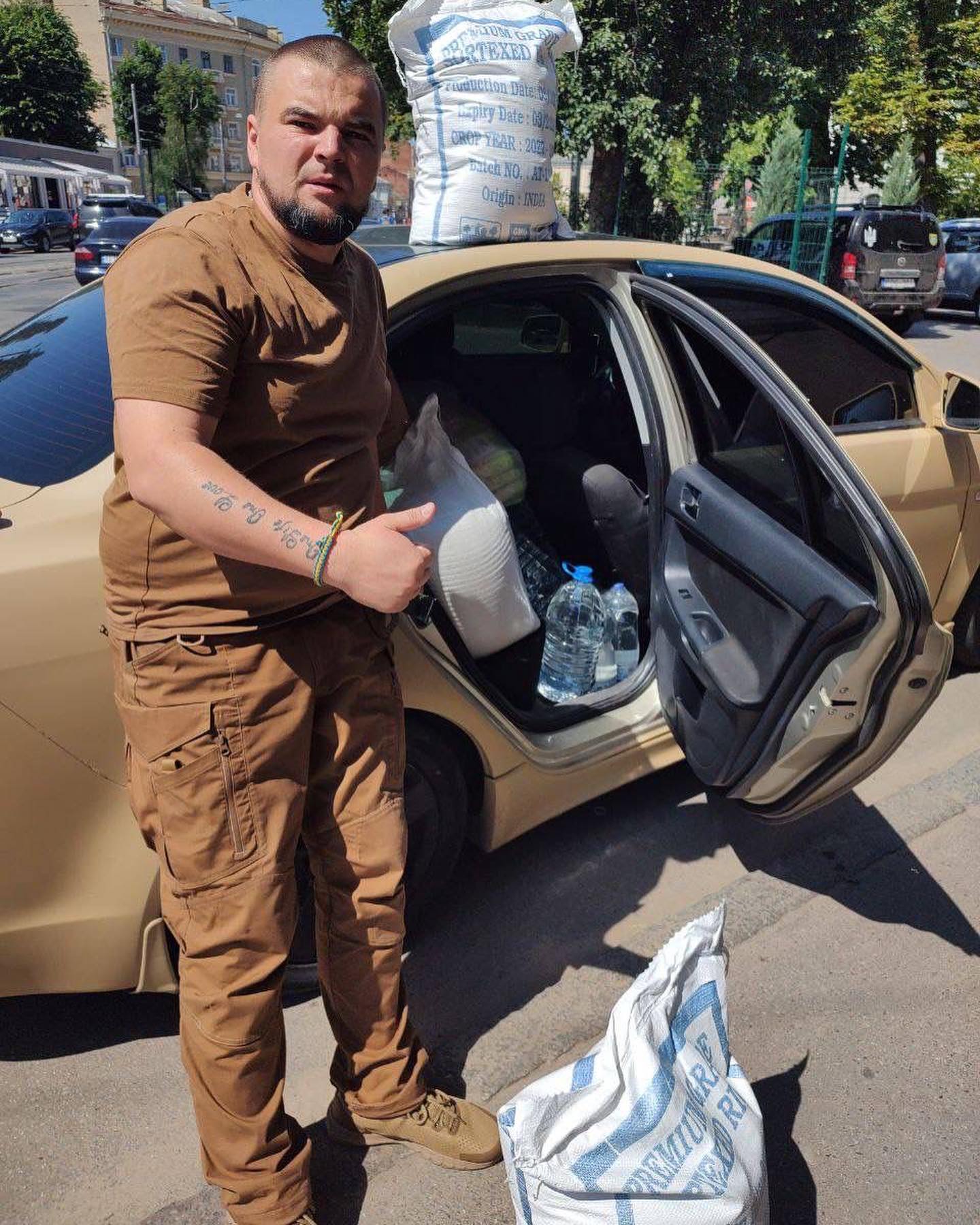 a man standing next to a car with bags of water.