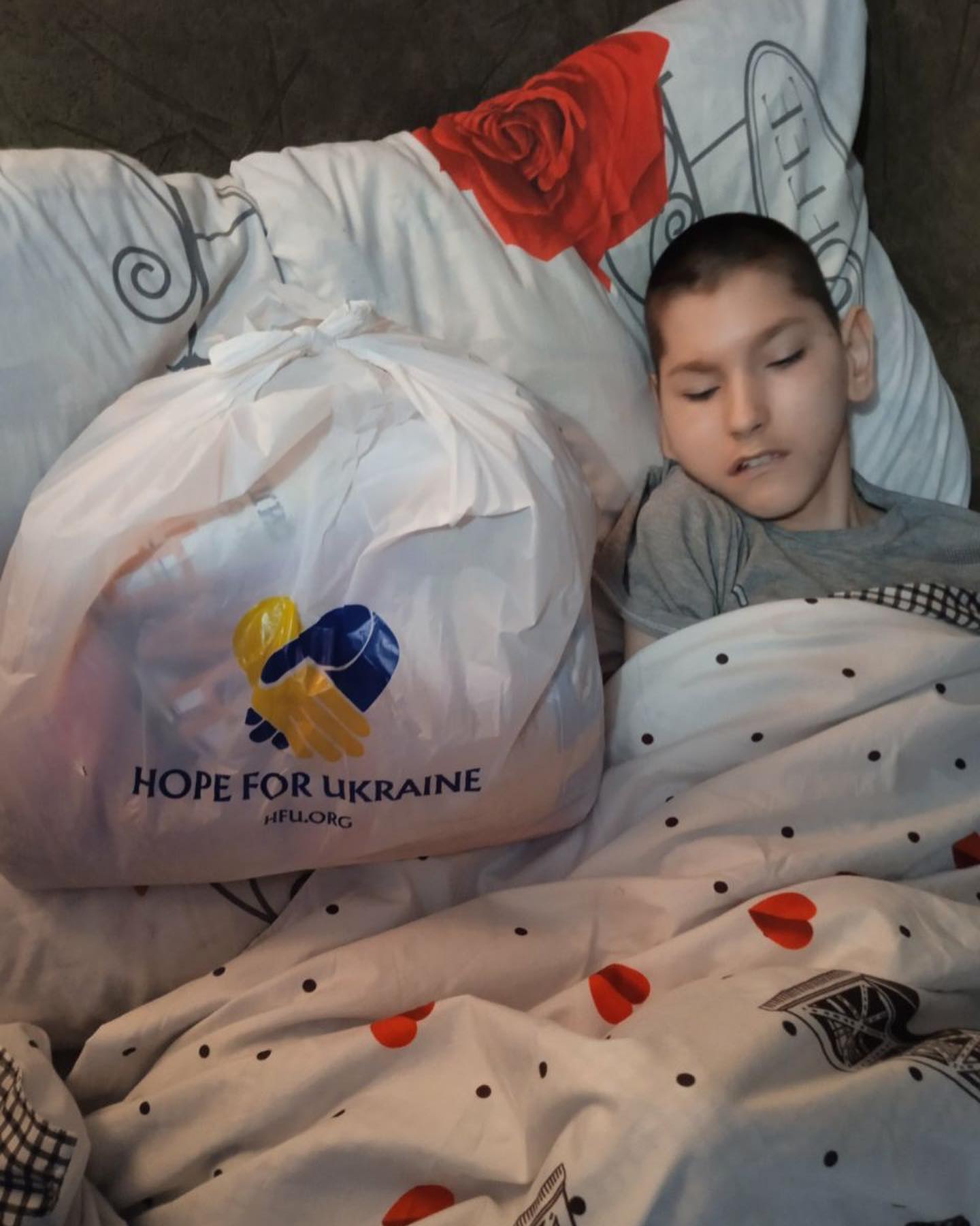 a boy is sleeping next to a bag with the word hope for ukraine.