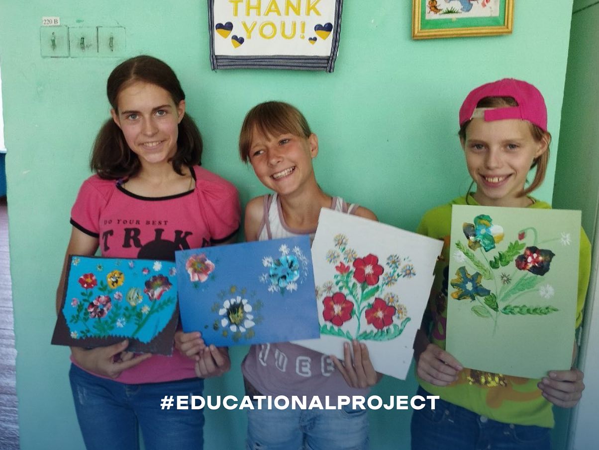 A group of girls are holding up flowers with the words education project.