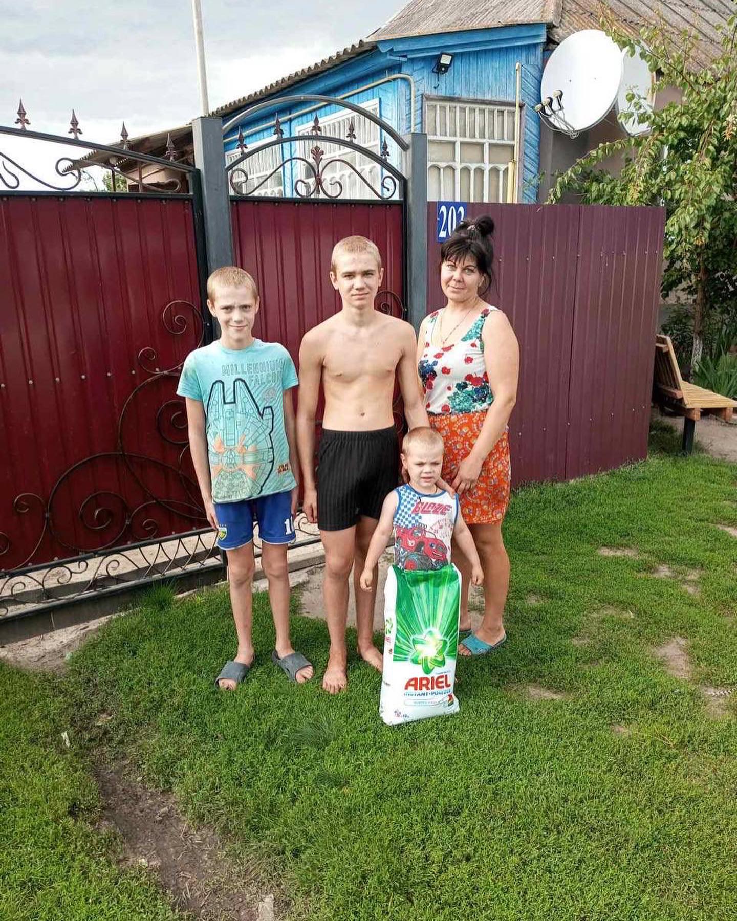 a family standing in front of a yard with a bag of food.