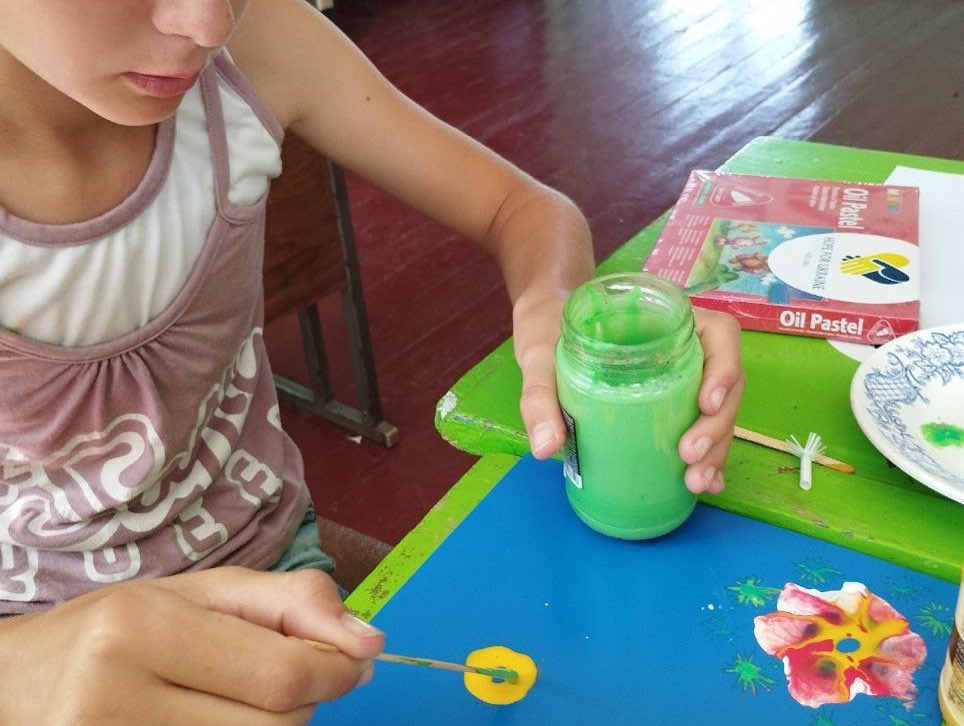 A girl is painting with paint on a table.