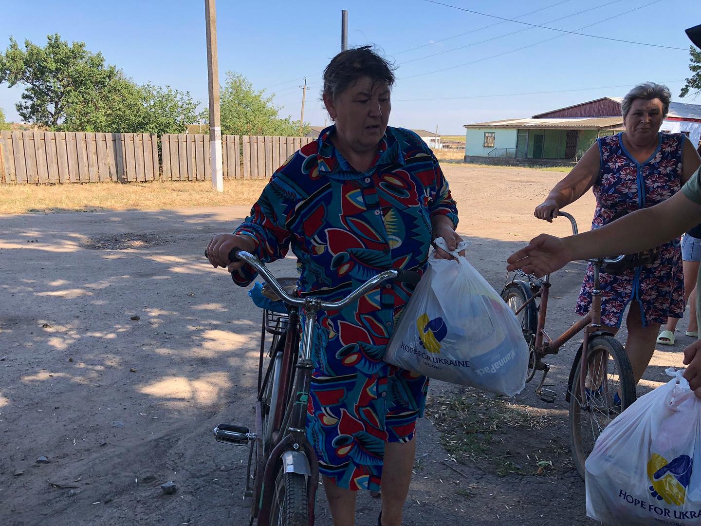 A woman is standing next to a man on a bike.