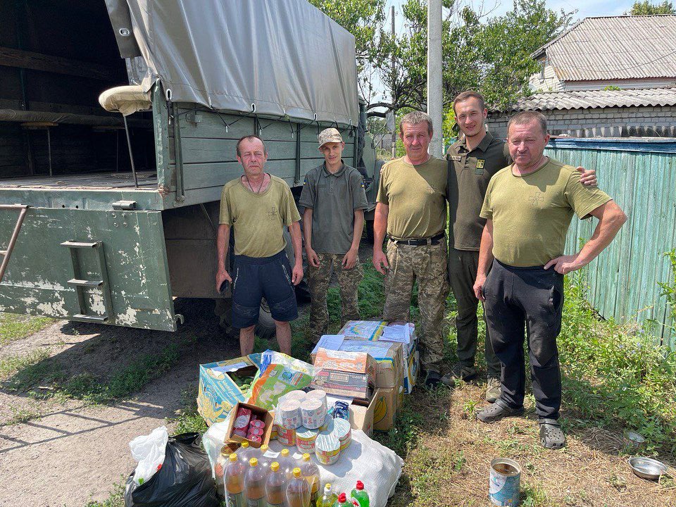A group of men standing next to a truck full of food.