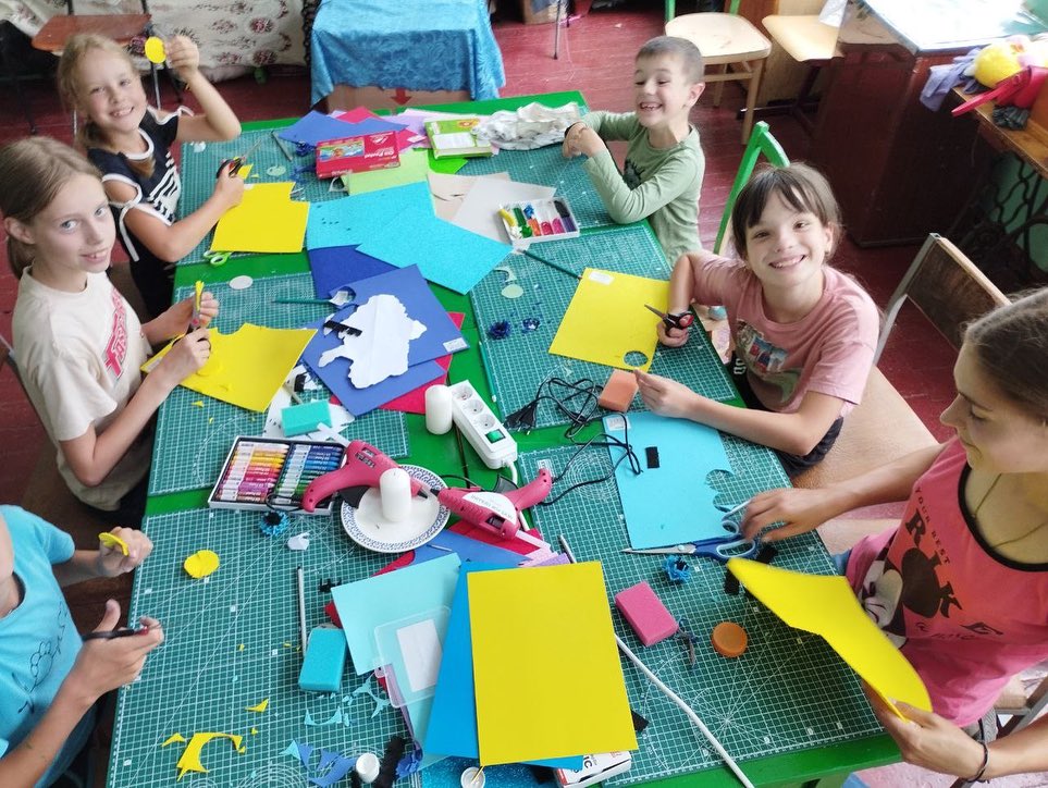 A group of children sitting around a table making crafts.