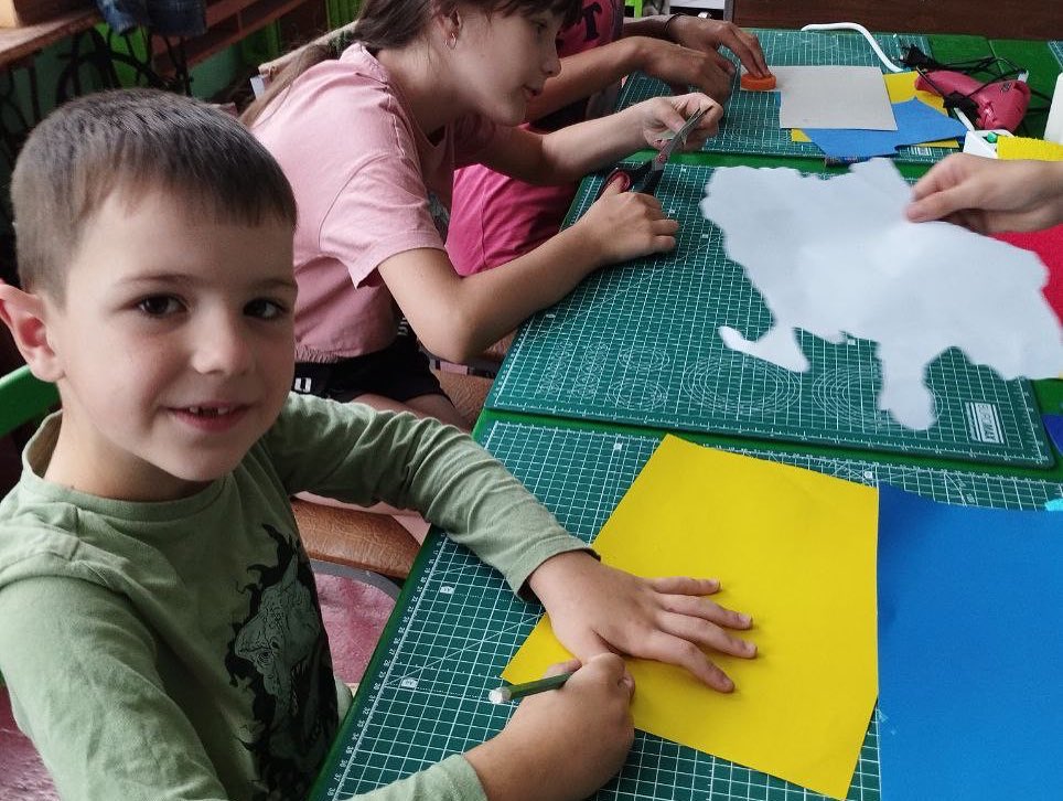 A group of children are making paper crafts at a table.