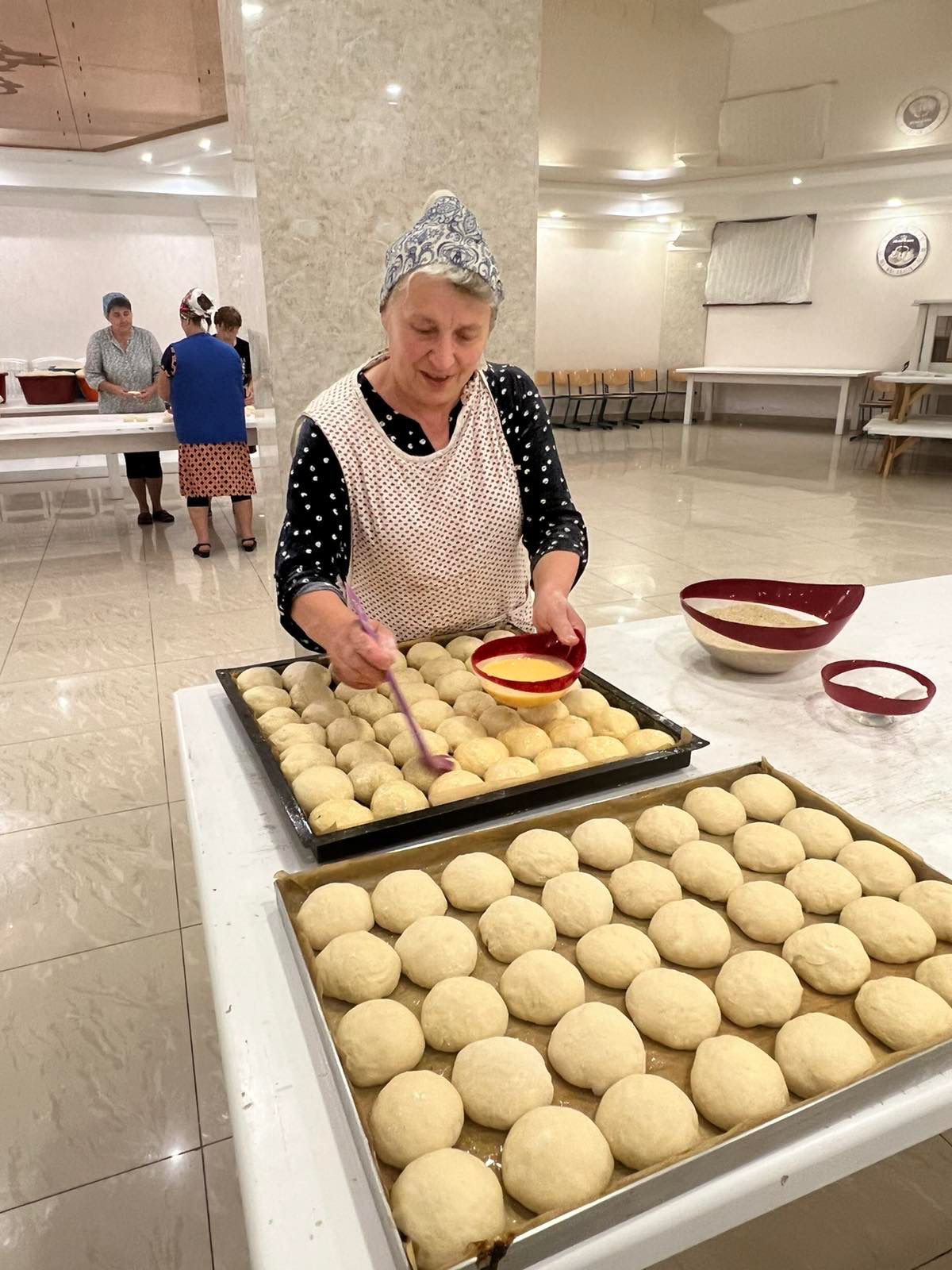 A woman is preparing a tray of dough.