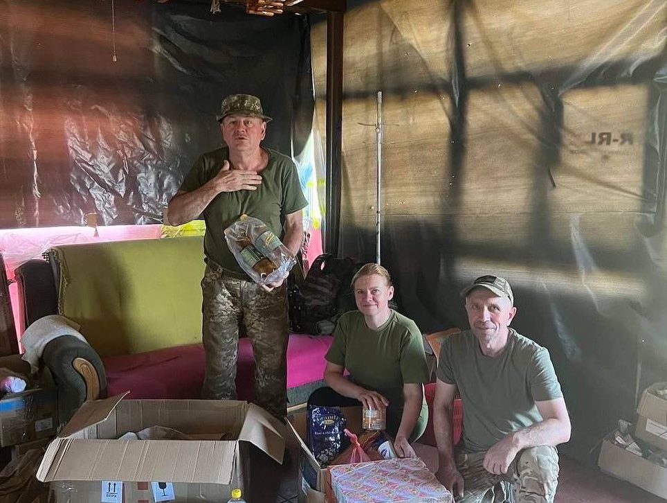 A group of soldiers are posing in front of a box of food.