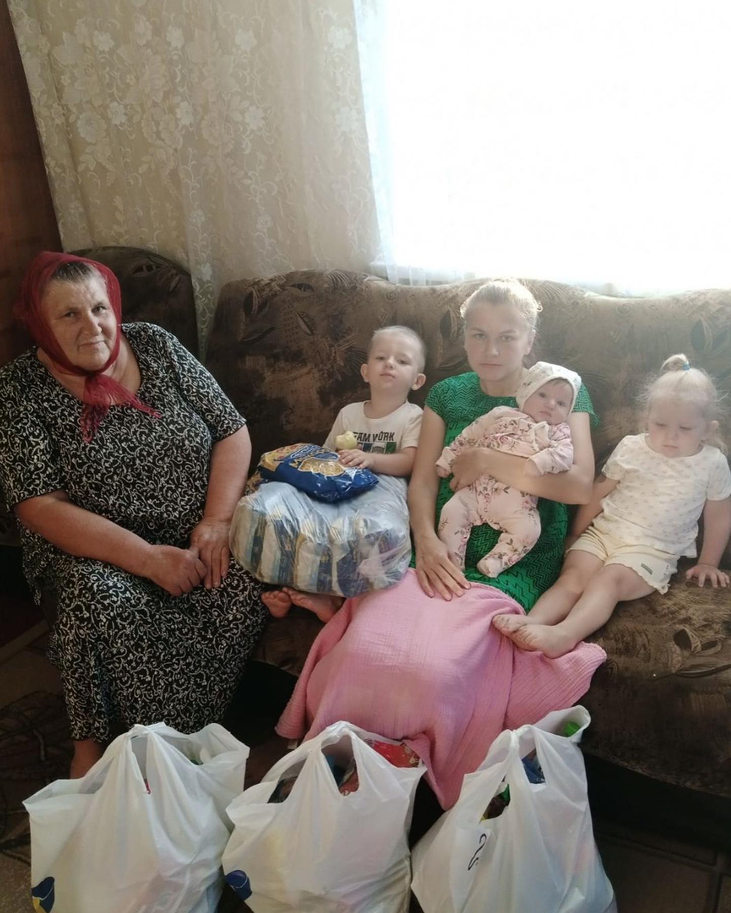 A group of people sitting on a couch with bags of groceries.