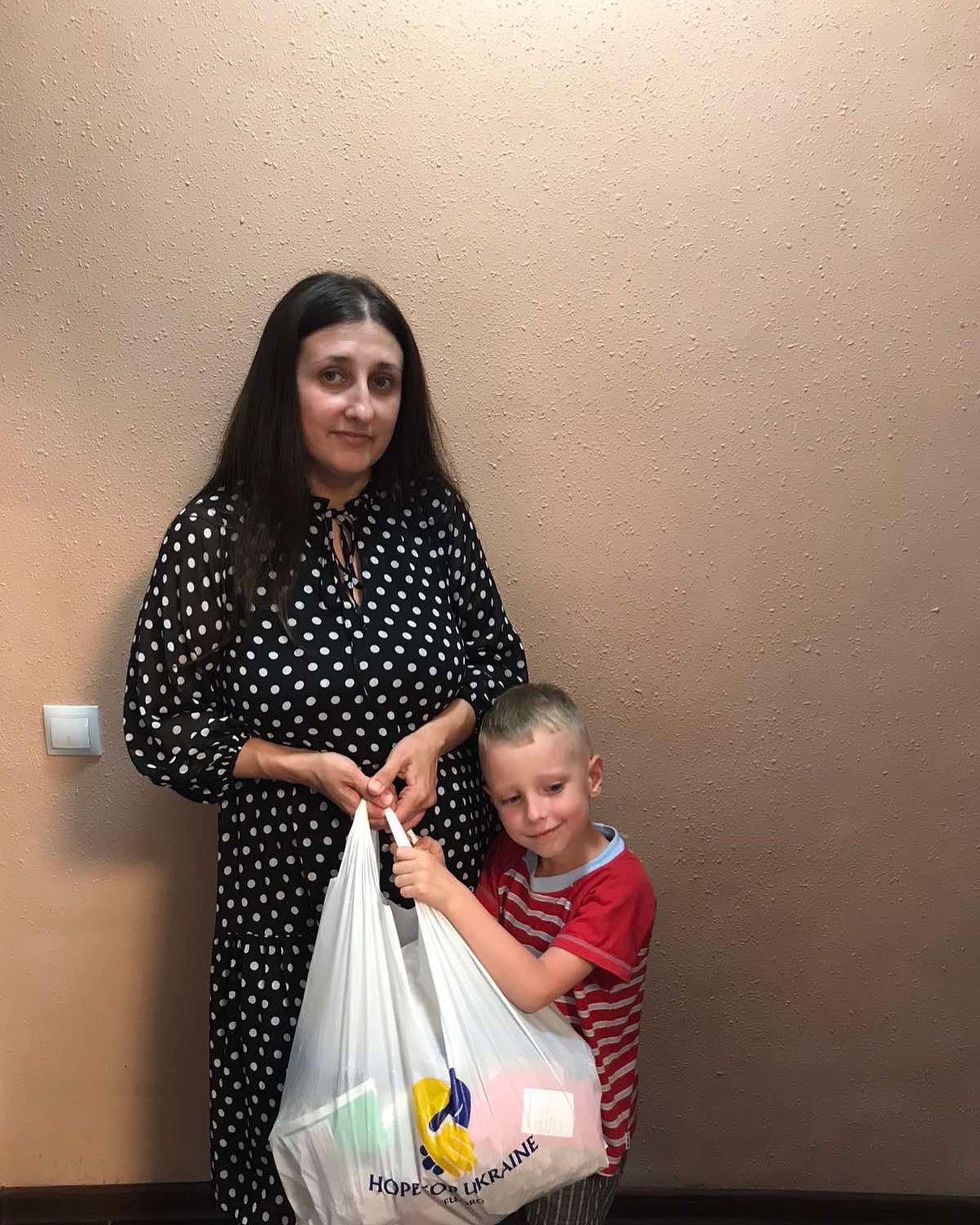 A woman and a boy holding bags of food.